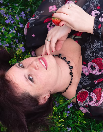 Marilyn Barr among wildflowers, holding a strawberry